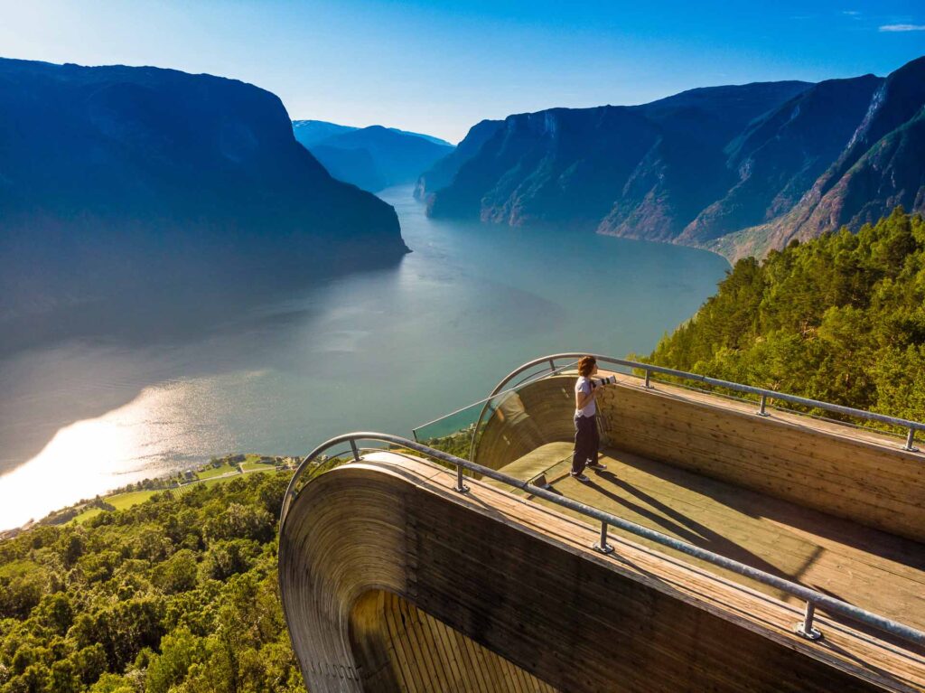 Tourist enjoying fjord view of Aurlandsfjord landscape from Stegastein viewing point. National tourist route Aurlandsfjellet.
