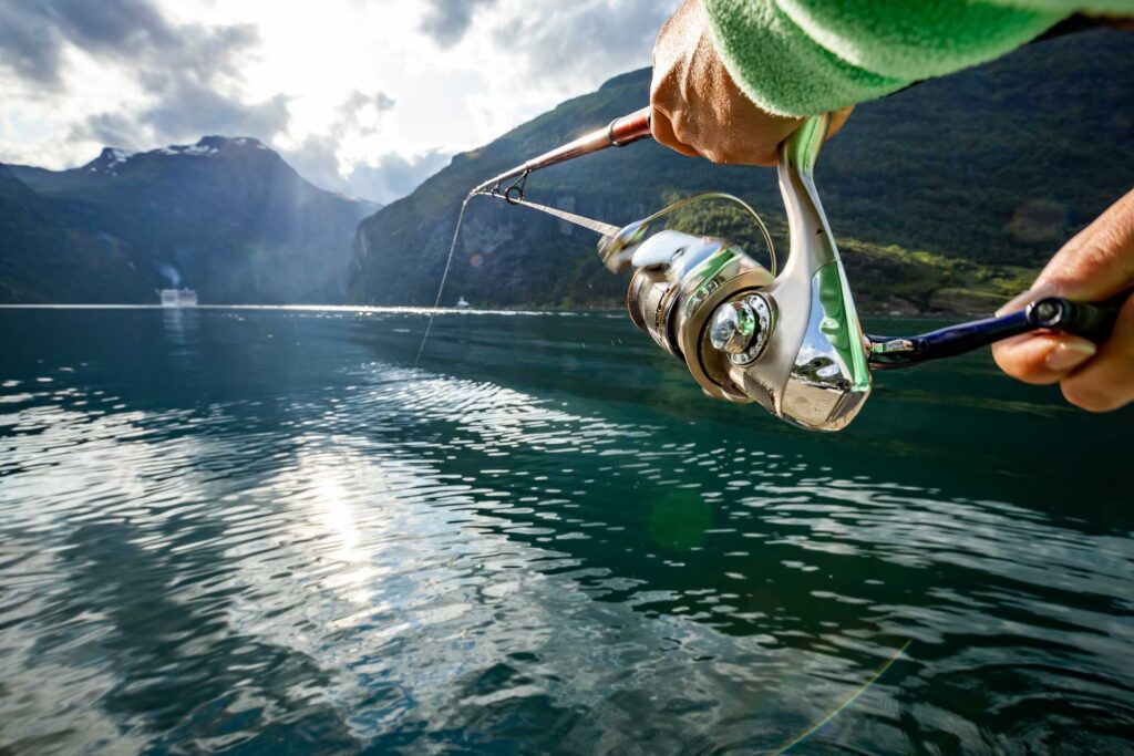 Woman fishing on Fishing rod spinning in Norway. Fishing in Norway is a way to embrace the local lifestyle. Countless lakes and rivers and an extensive coastline means outstanding opportunities...