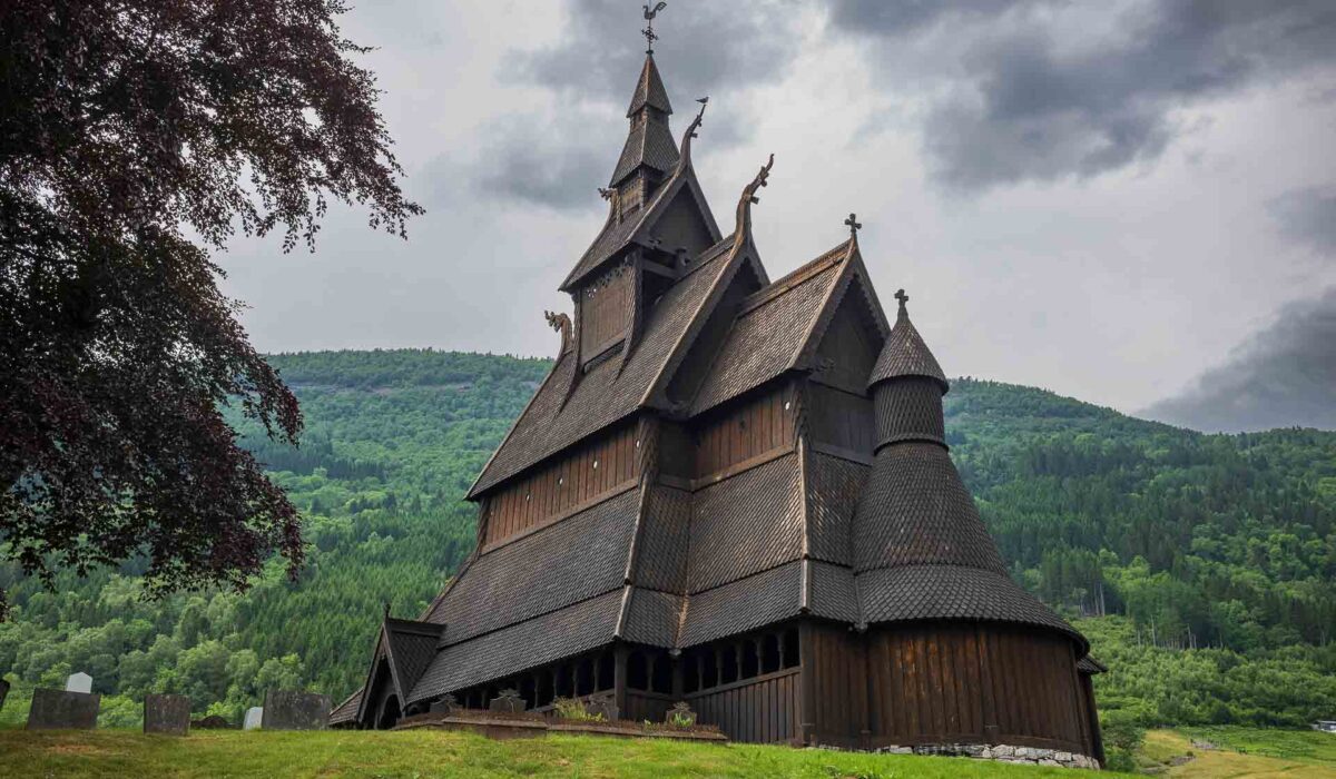 Hopperstad Stave Church, an ancient wooden stave church dating back to the 1100s, located in Røysane, Norway, photographed with moody storm clouds on an overcast summer day.