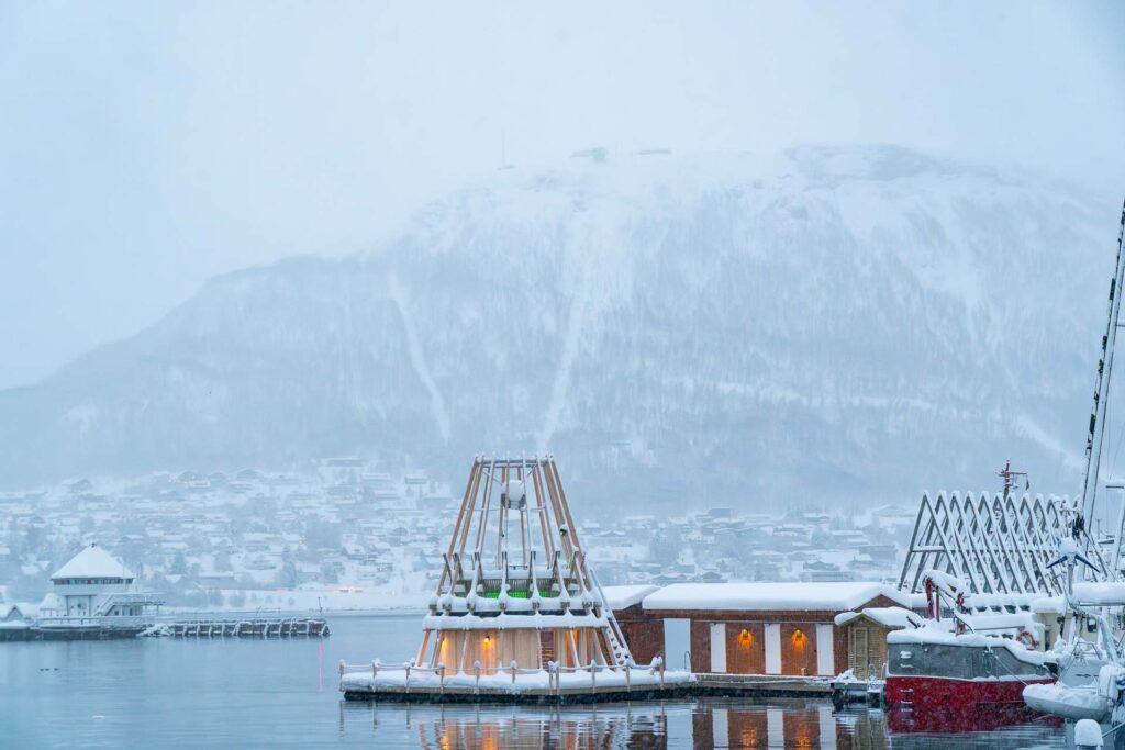 Tromsø, Norway, city harbor with a sauna and bath, mainland and mountains in the background.