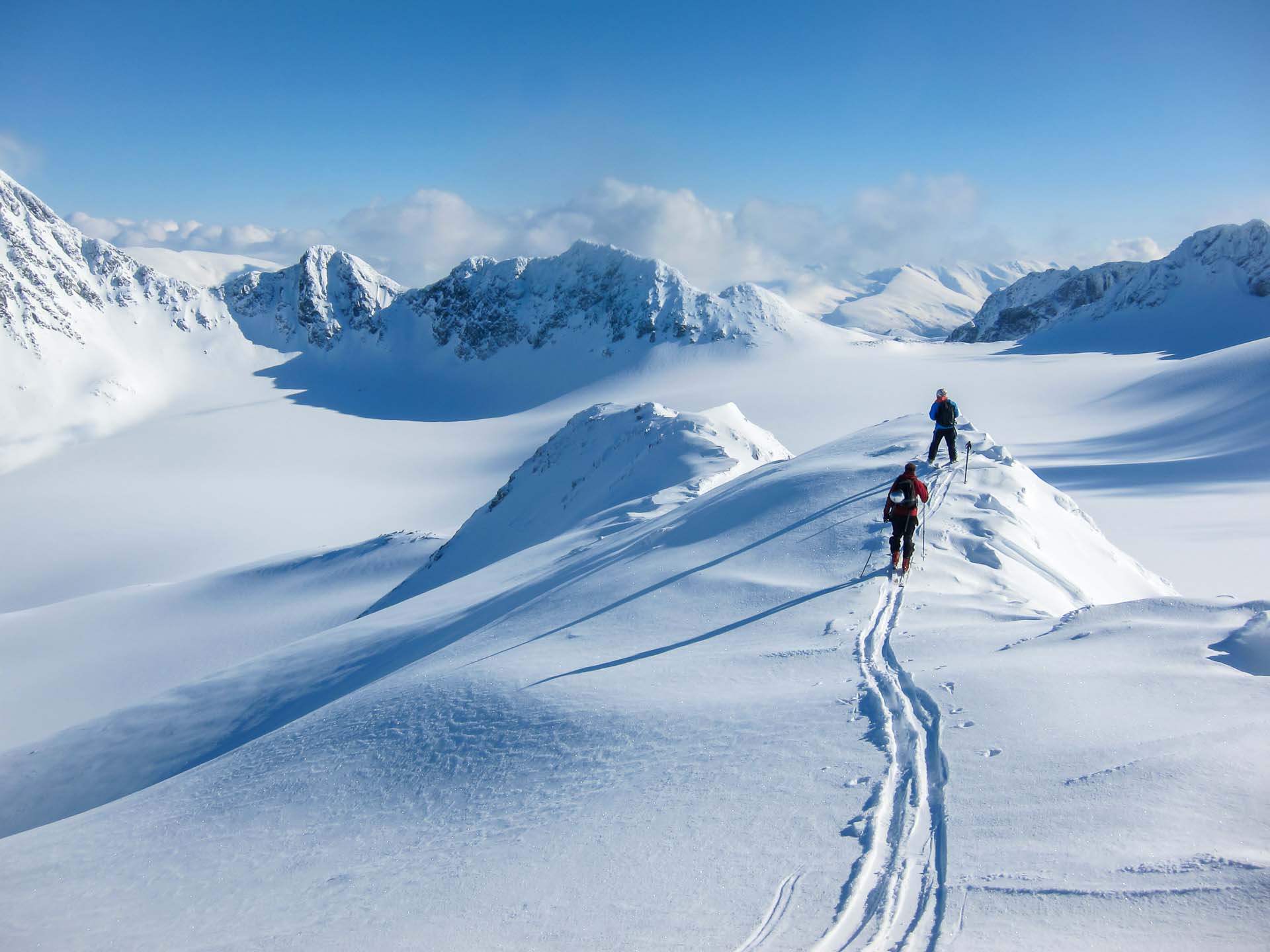 Tromsø Travel Guide 29 High altitude view of two skiers walking on a mountain ridge in the Lyngen Alps, Norway